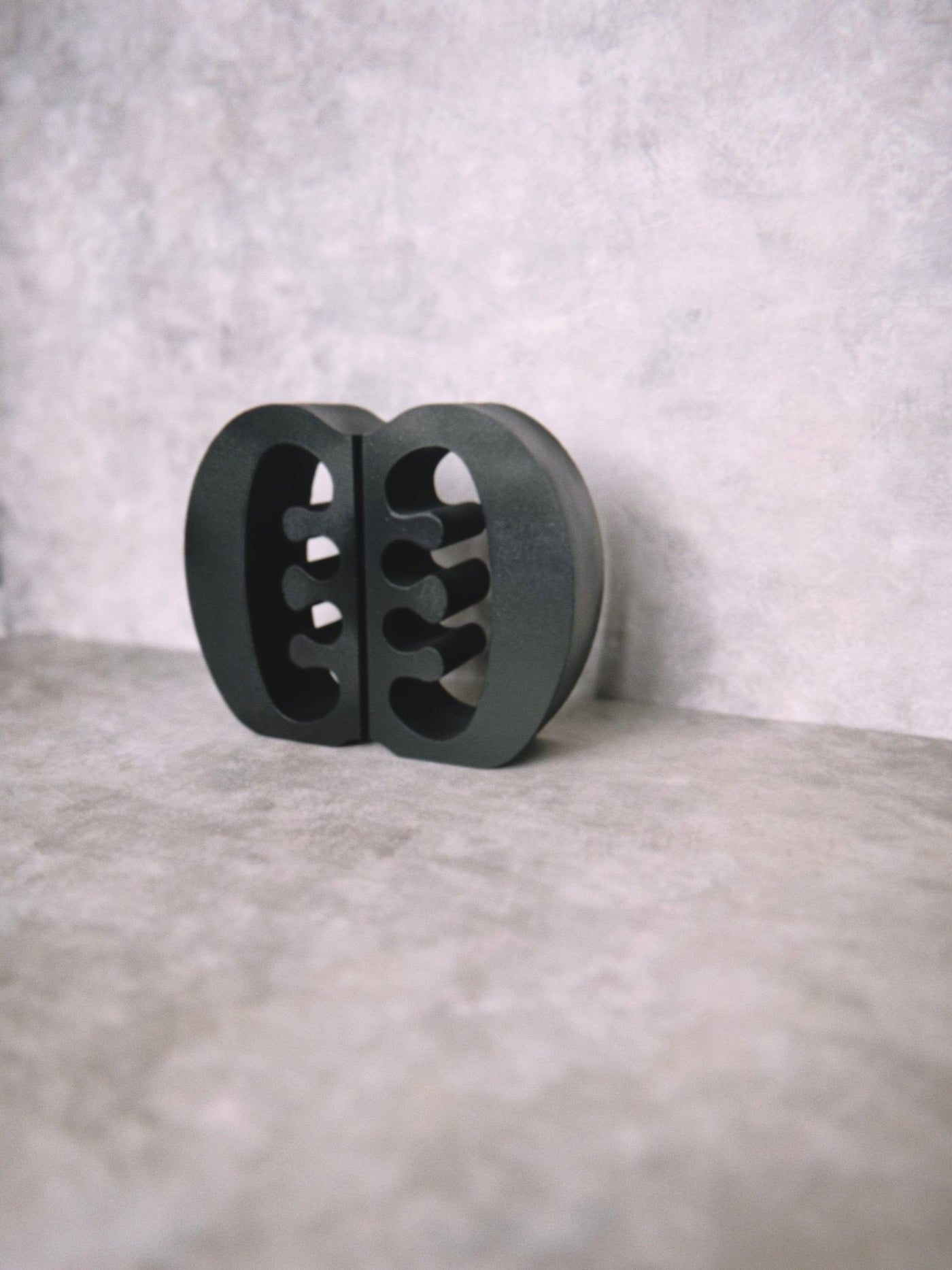 Decorative black Ese Ne Tekrema adinkra bookends on a light gray lime wash background.