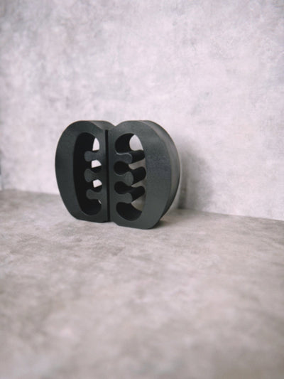 Decorative black Ese Ne Tekrema adinkra bookends on a light gray lime wash background.